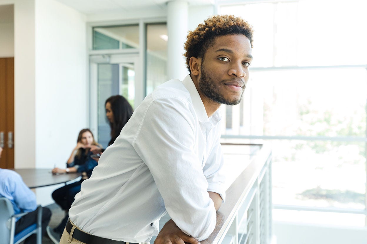 The serious young adult businessman steps away from a contentious meeting with colleagues.