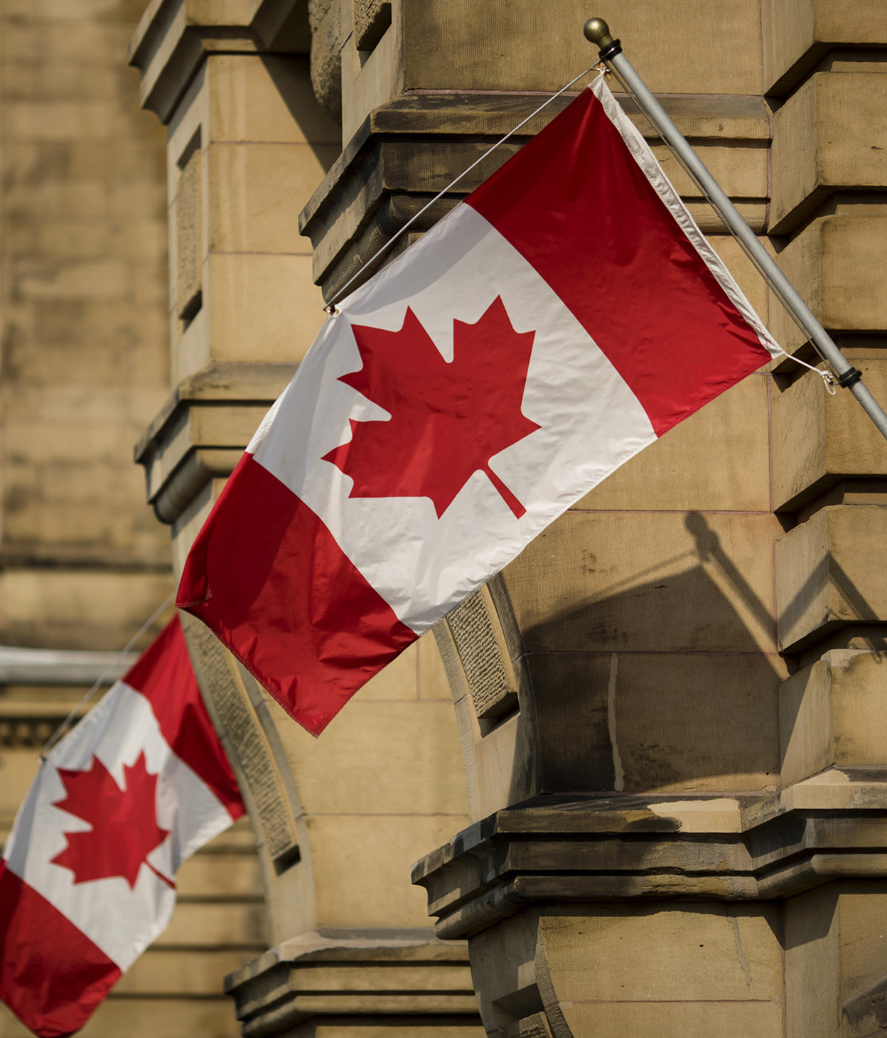 Canadian flags hang on display outside the Office of the Prime Minister and Privy Council building in Ottawa, Ontario, Canada.