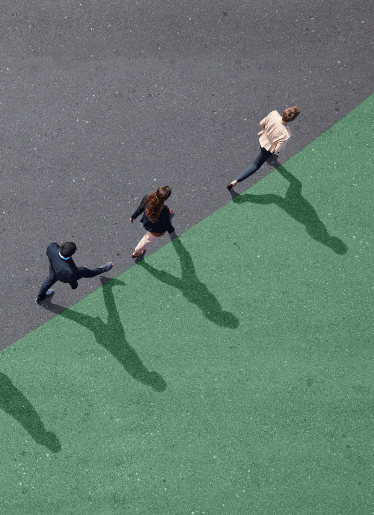 Group of professionals walking diagonally along a green painted section of a basketball court.