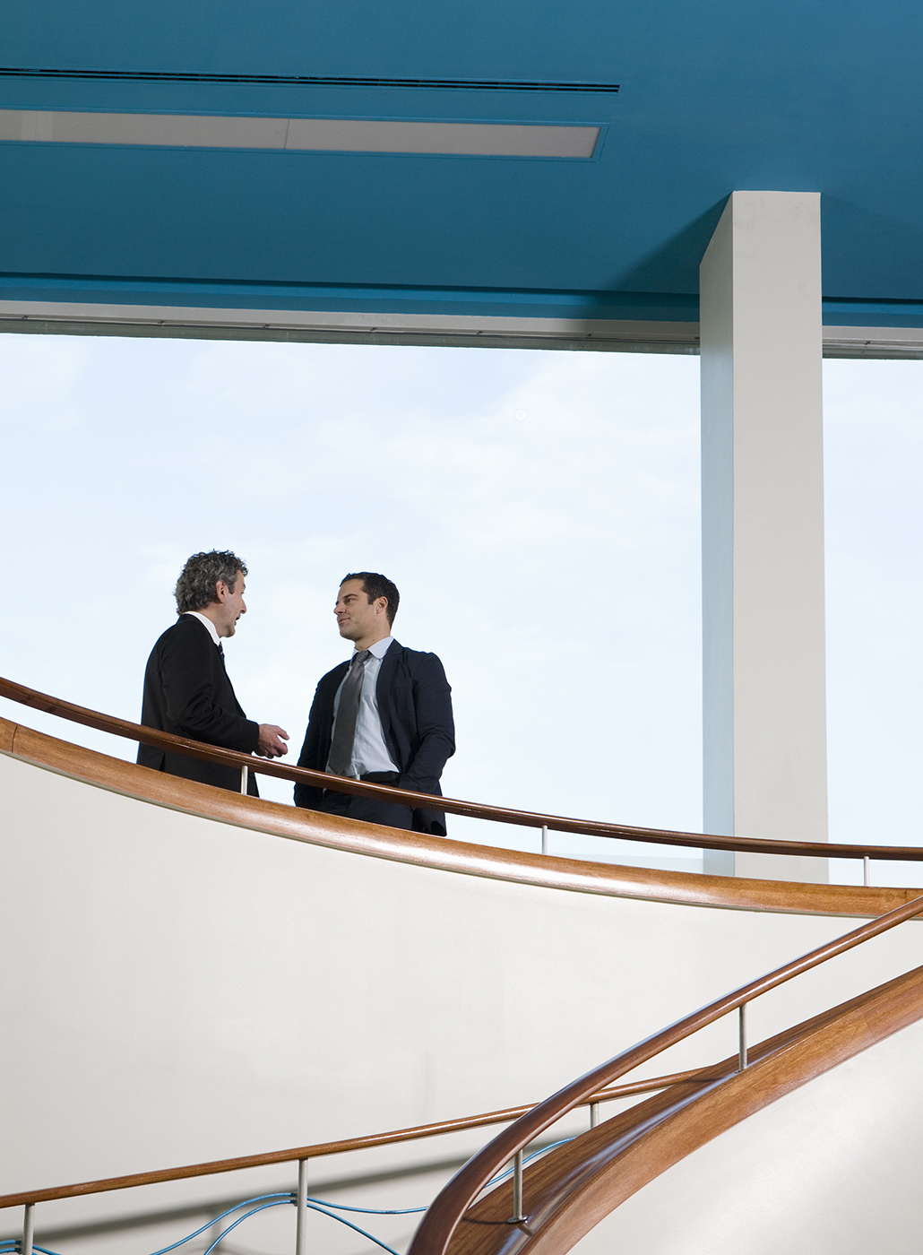 Dos hombres de negocios conversan en un balcón.