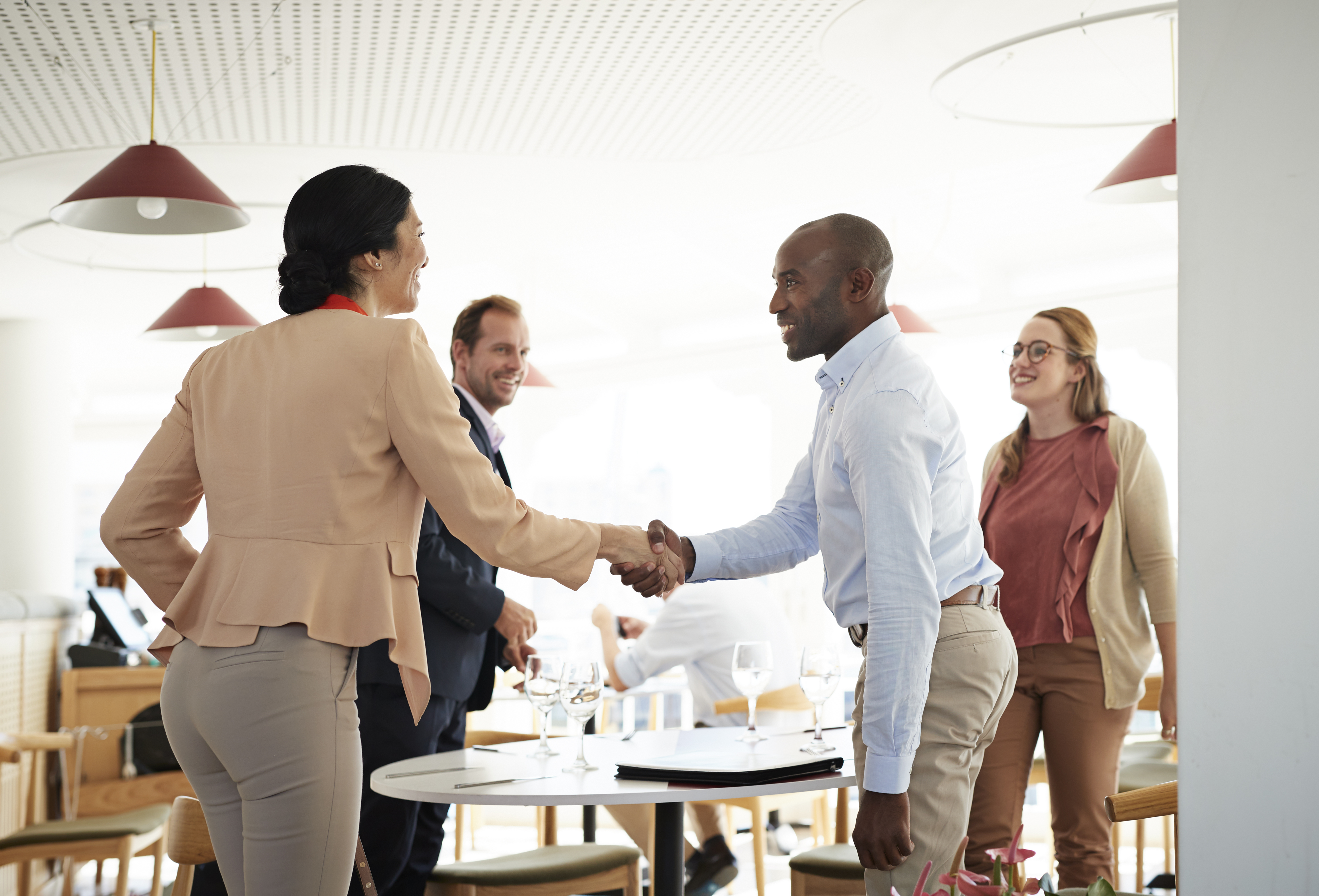 Business people enjoy a casual meeting at a restaurant table, finalizing a deal with a handshake.