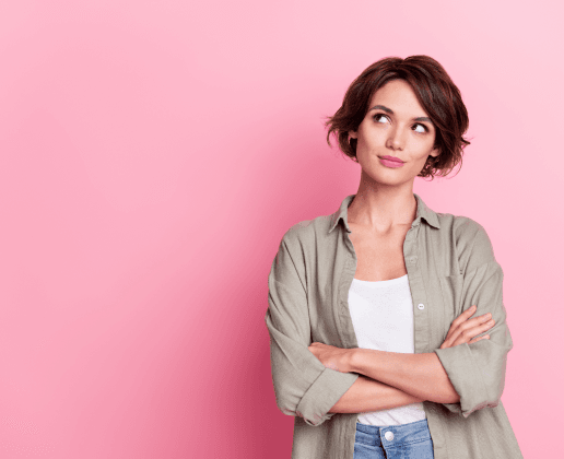 Woman with an exaggerated expression stands in front of a pink wall.